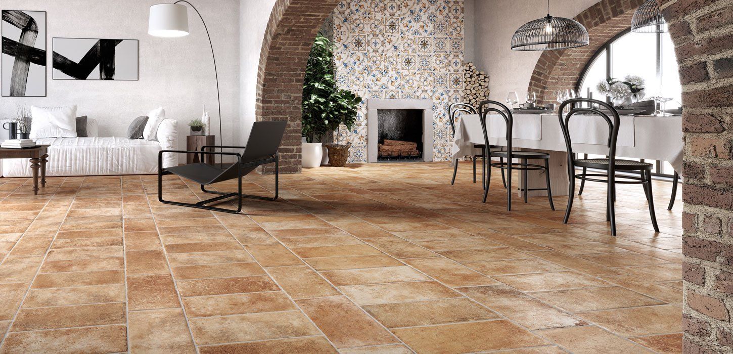 Interni rustici con archi e pavimenti in mattoni a vista. Al centro si trova un camino, sulla destra si trova la zona pranzo.