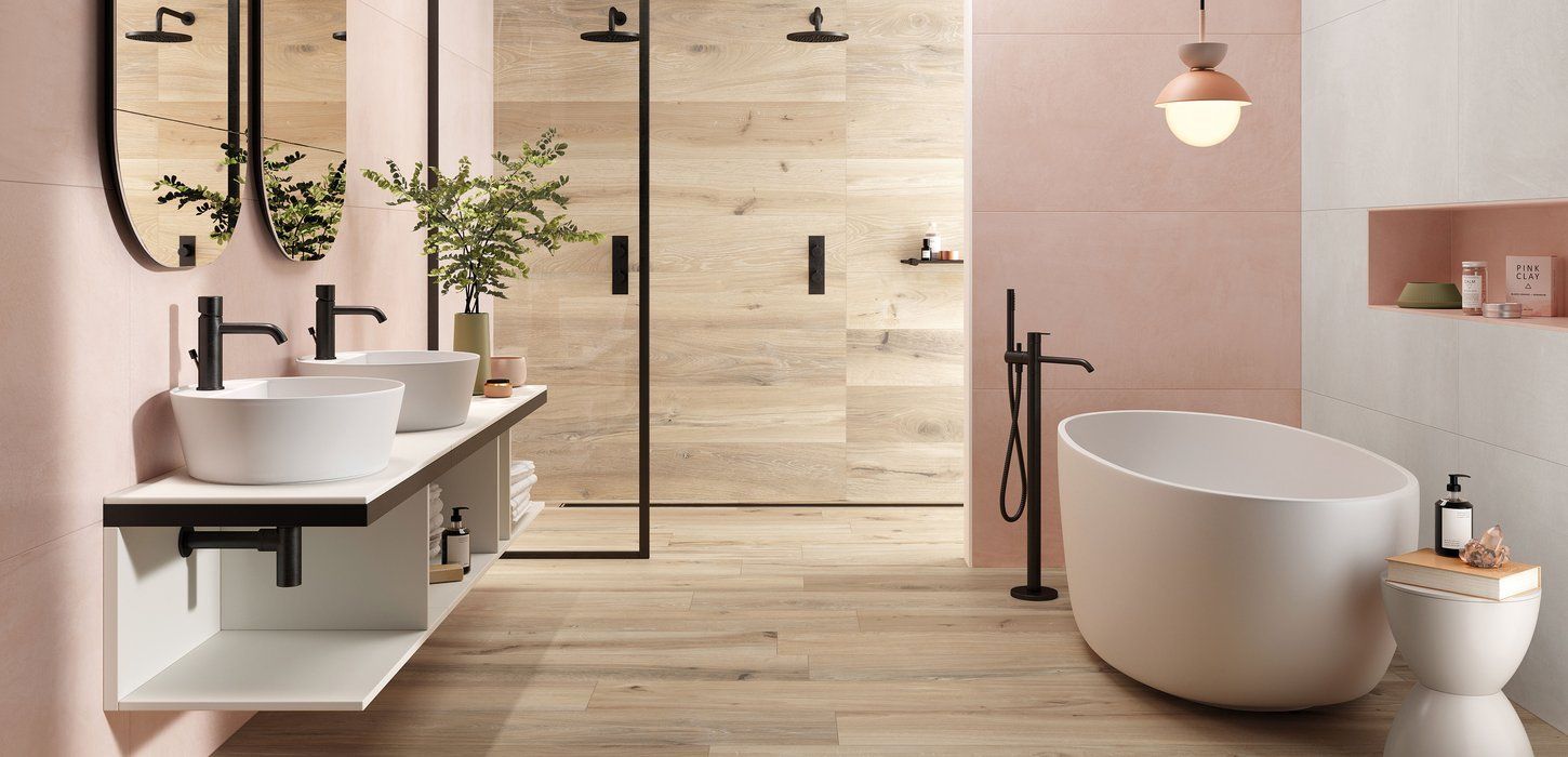 Bagno moderno con lavandini bianchi, vasca da bagno indipendente e pareti rosa.