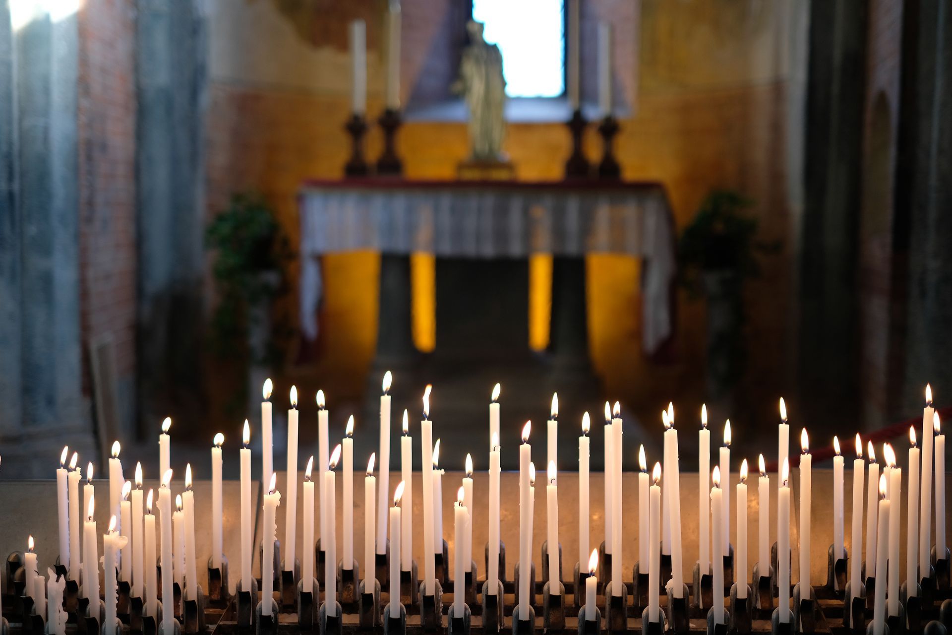 Una fila di candele accese davanti a un altare in una chiesa