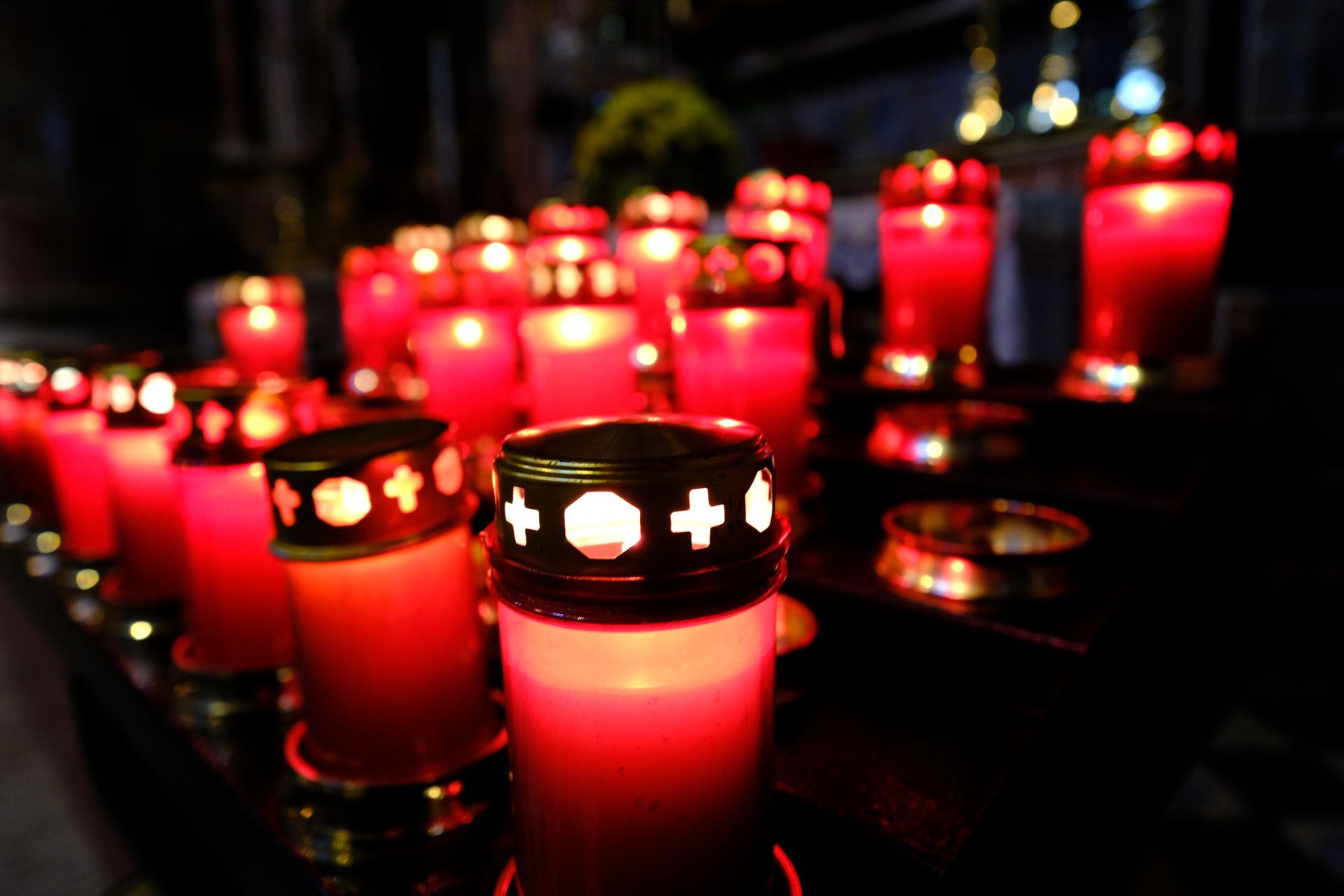 Una fila di candele rosse è accesa in una stanza buia.