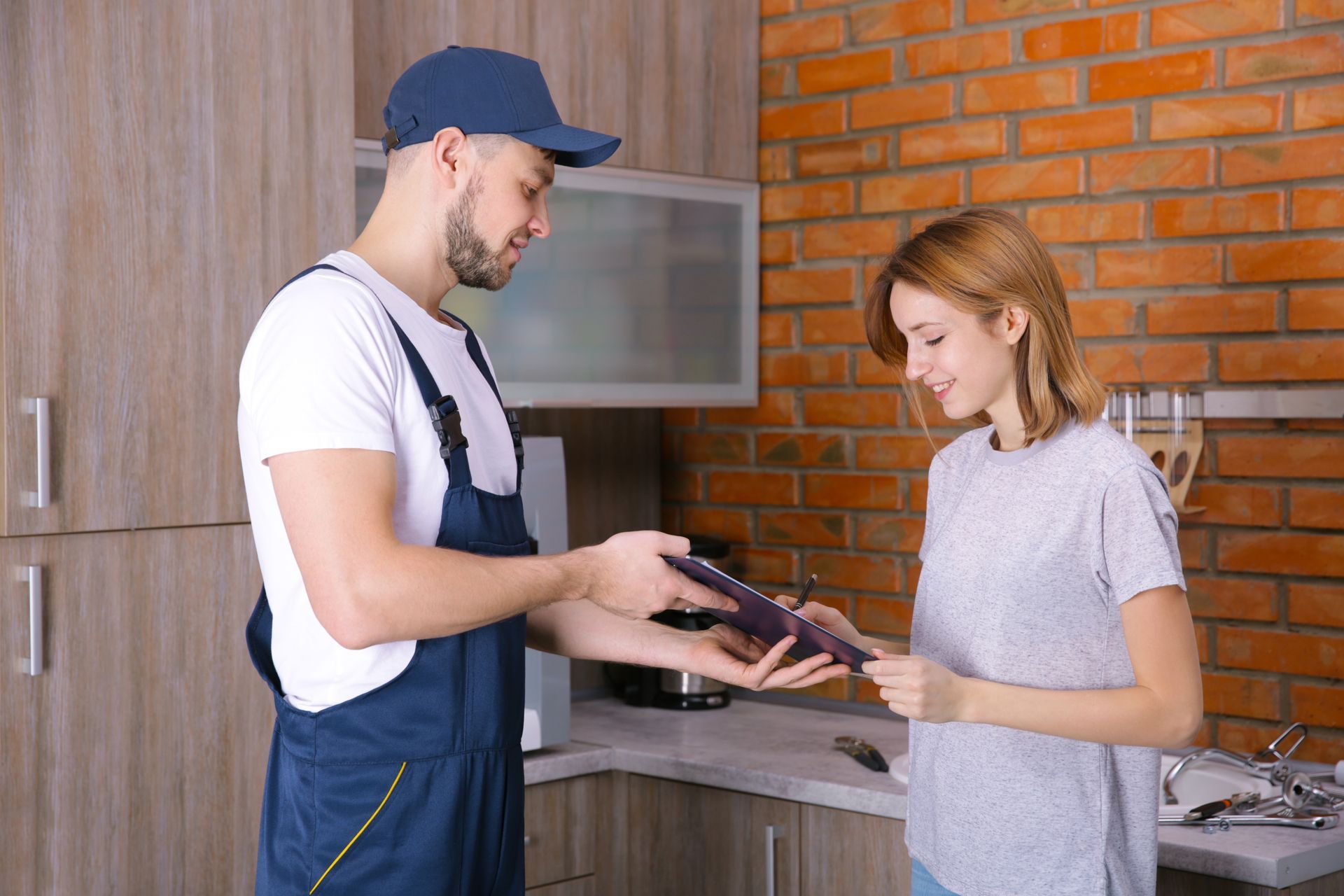 Delivery worker handing a package to a woman in a kitchen
