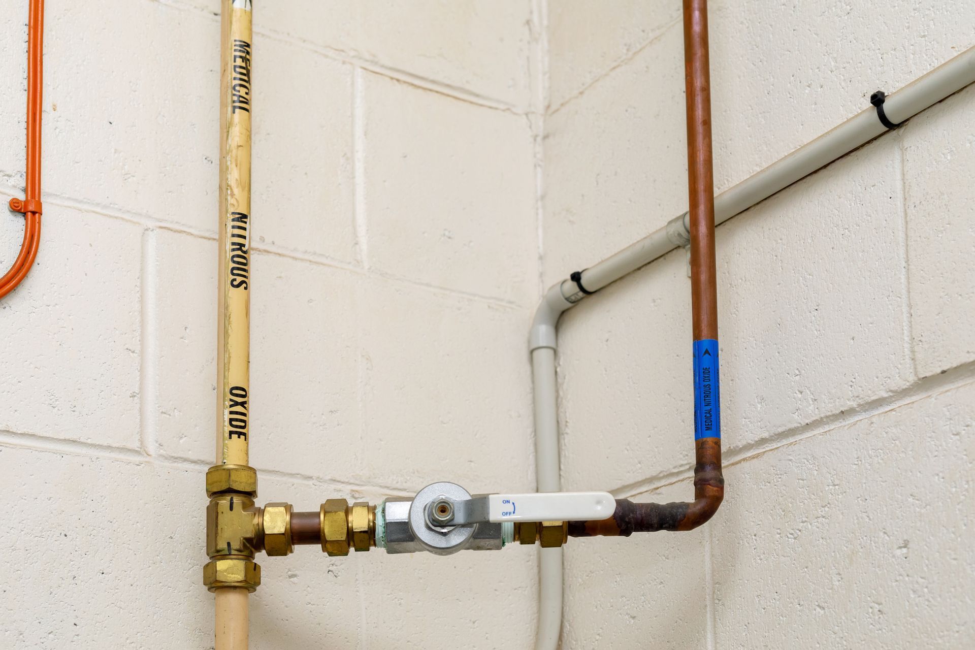 Copper pipes and a water valve on a white wall in a utility area