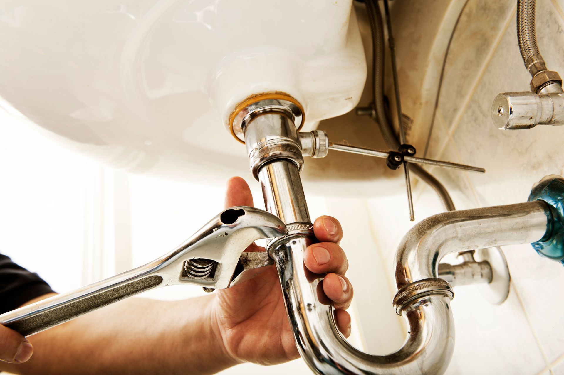 Under-sink plumbing with white PVC pipes and a drain trap in a cabinet