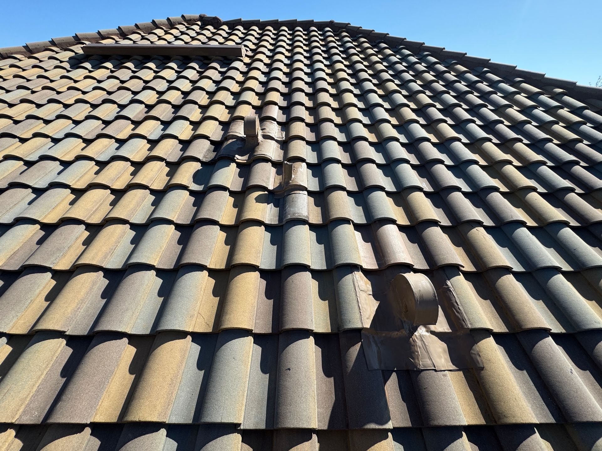 Vent pipe on a roof with damaged shingles and dark sealant. Vent pipe on a roof with damaged shingles and dark sealant.