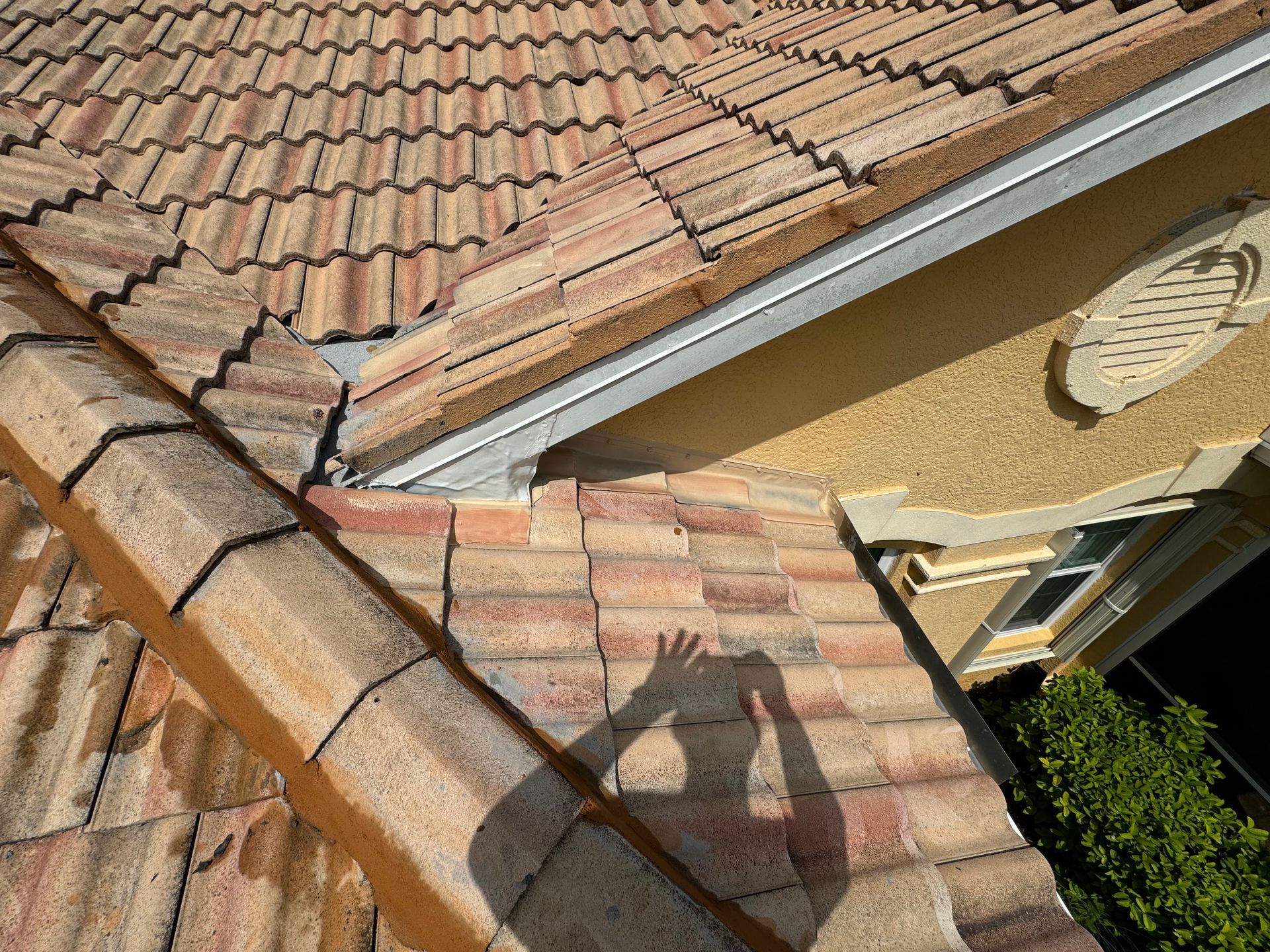 A close-up of a clay tile roof with a shadow of a person taking a photo. A close-up of a clay tile roof with a shadow of a person taking a photo.