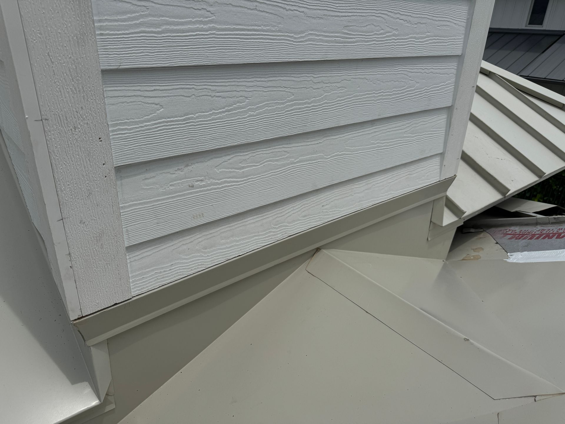 Light gray siding and trim on a structure's exterior, meeting a light gray metal roof.