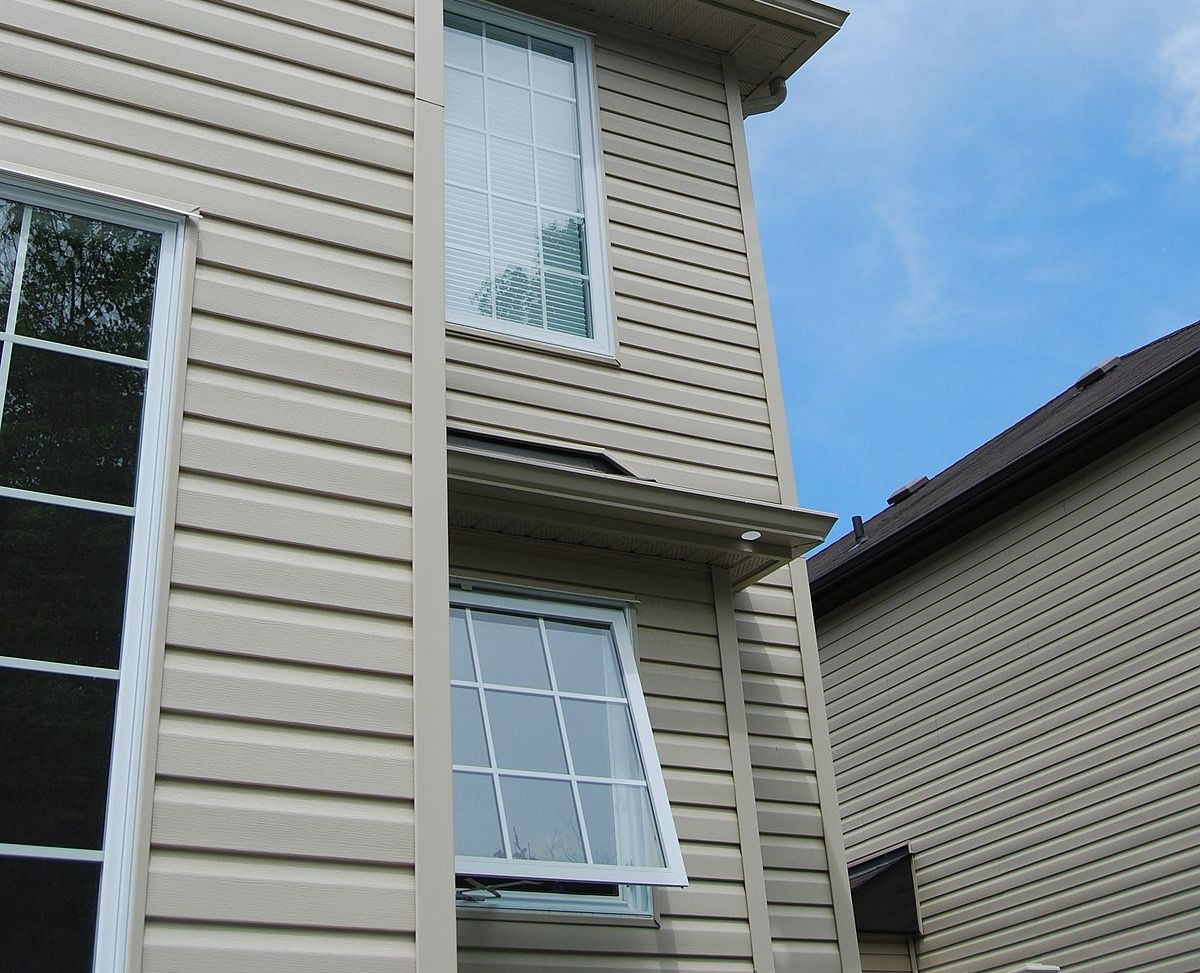 A group of workers installing siding on a house.