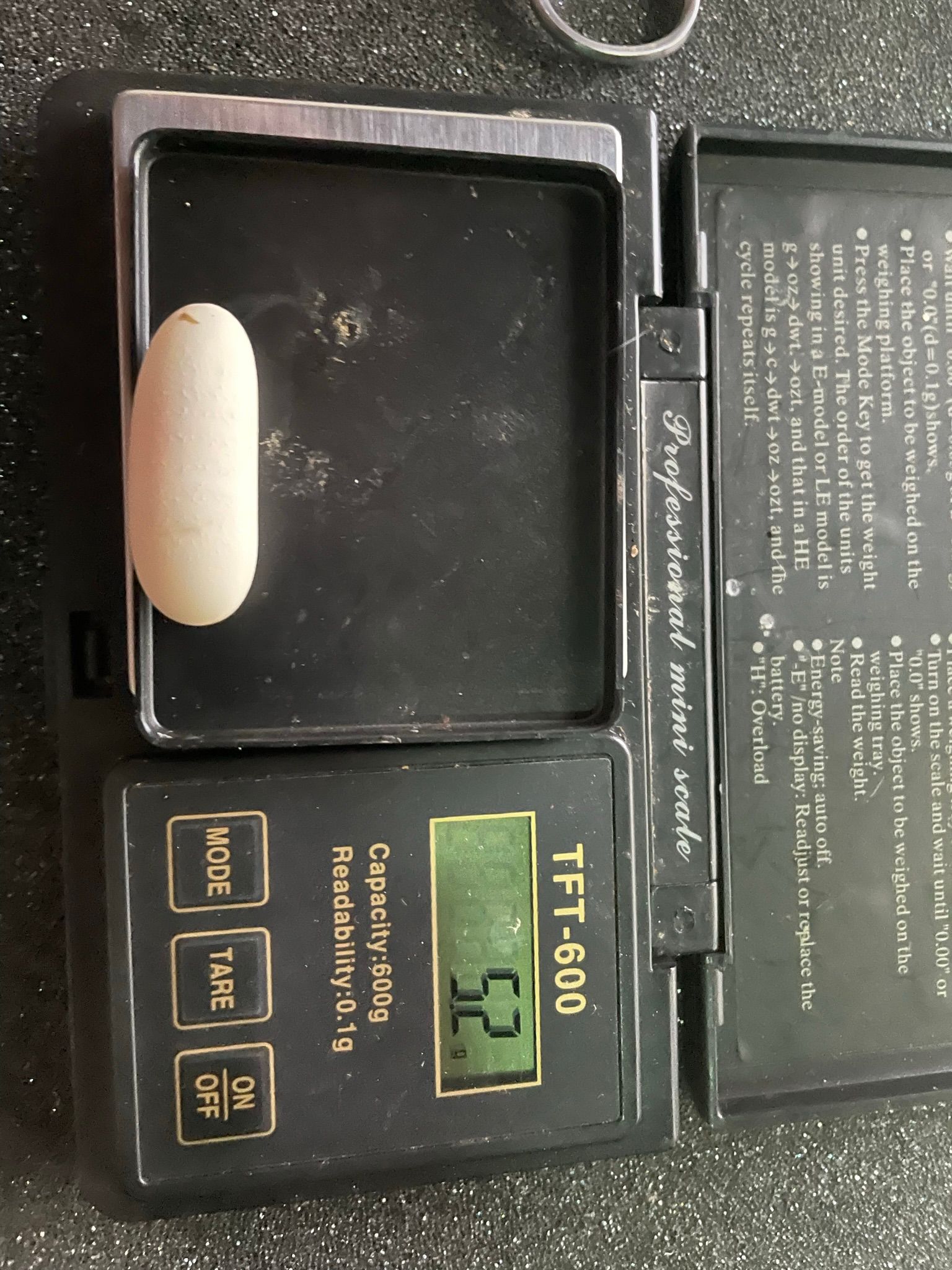 Nahaufnahme einer schwarzen digitalen Waage vom Typ TTF-600 mit grün hinterleuchtetem Display, das 0,0 anzeigt.