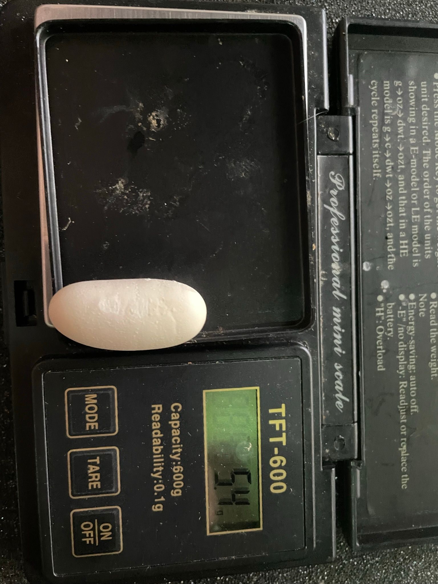 Geöffnetes Kompakttelefon mit cremefarbenem Radiergummi auf der Tastatur und goldenem TF-600-Etikett, Ansicht von oben.
