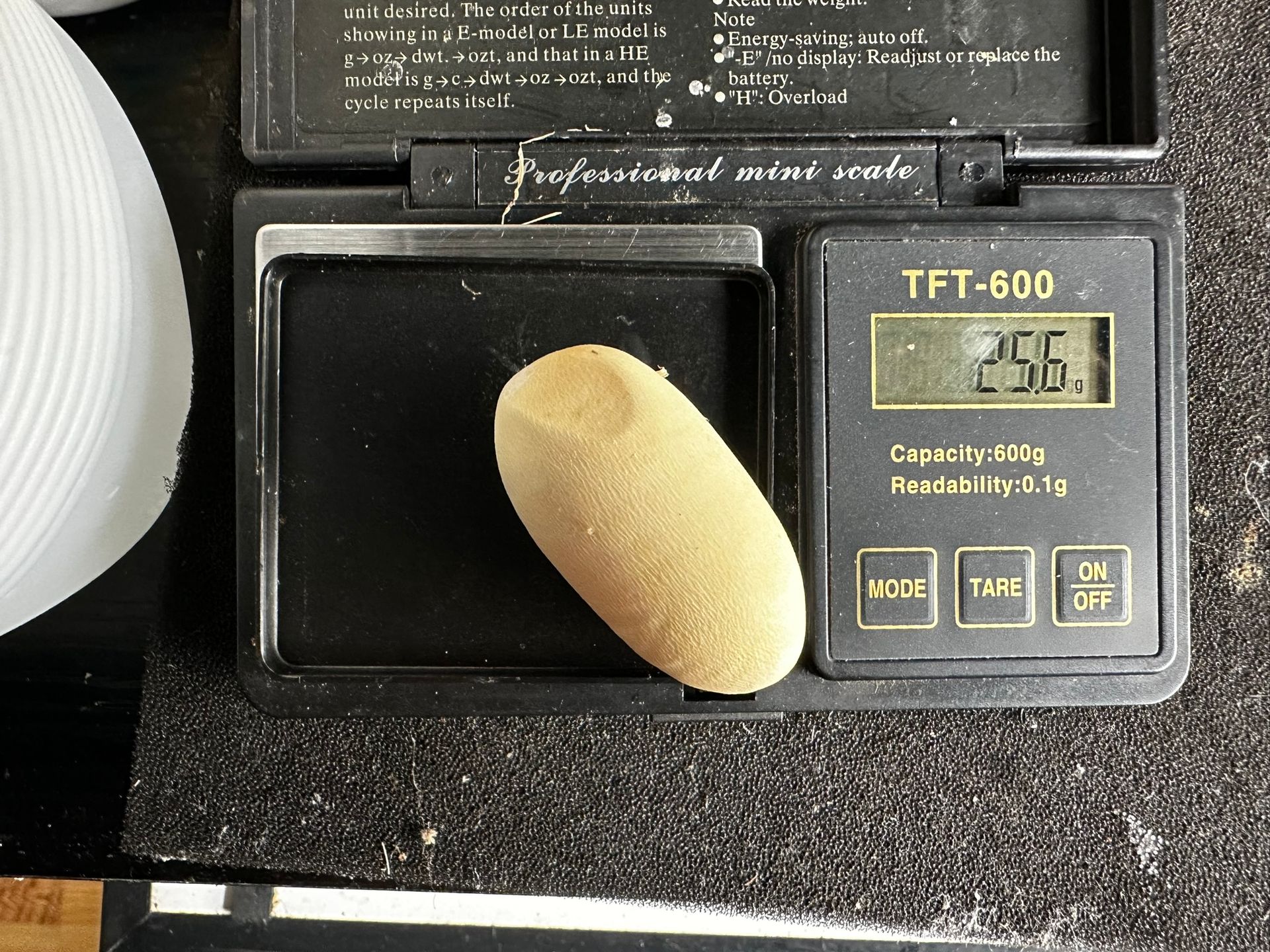 Ein beiger Schwamm lehnt an einer schwarzen digitalen Küchenwaage mit beleuchtetem Display.
