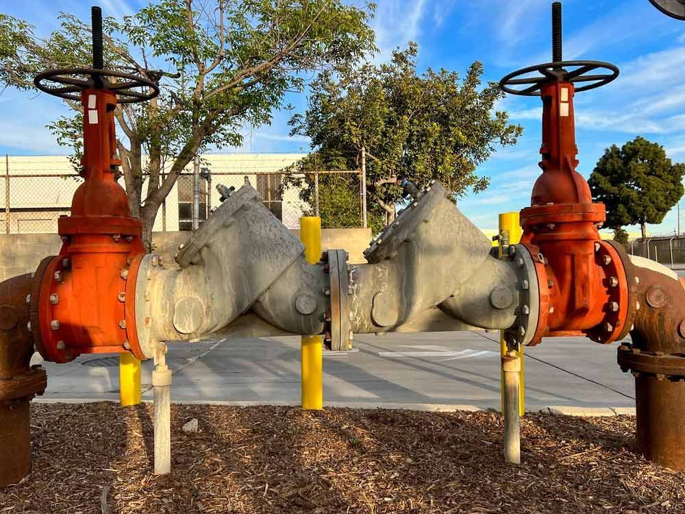 Two Red-handled Valves Flank Gray Pipes Outdoors — Keyeng in Slade Point, QLD