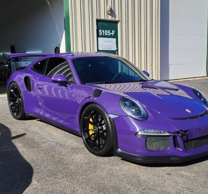 Purple Porsche 911 GT3 parked outside a building, side view with black wheels and yellow calipers