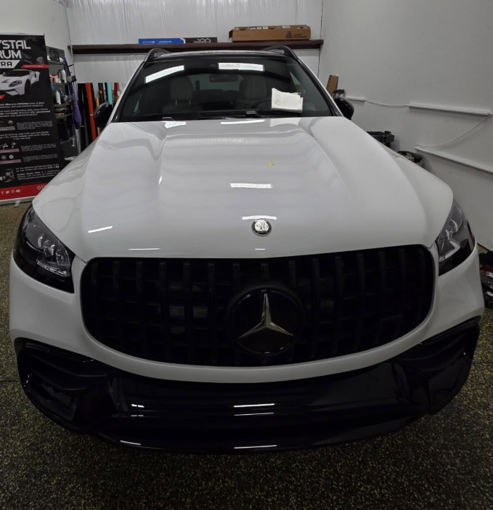 Front view of a white Mercedes-Benz SUV parked indoors in a garage