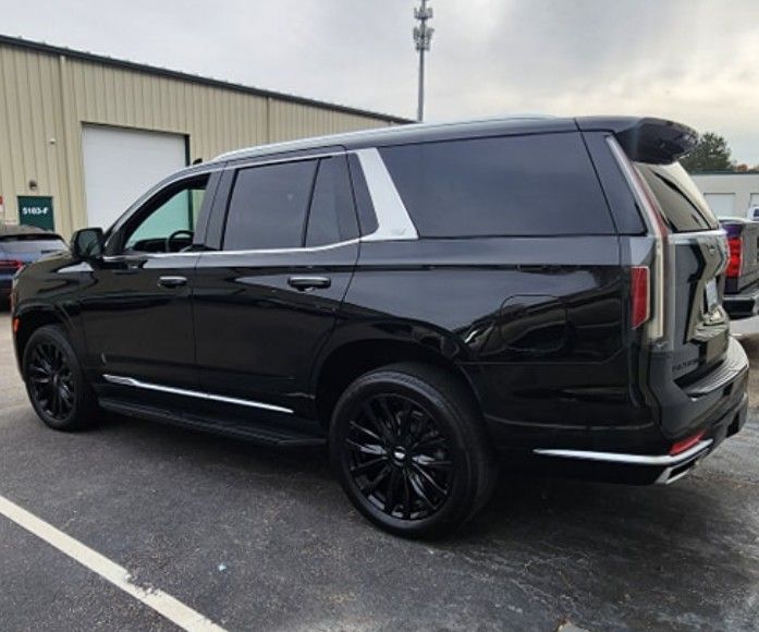 Black SUV parked beside a warehouse, shown from the rear side.