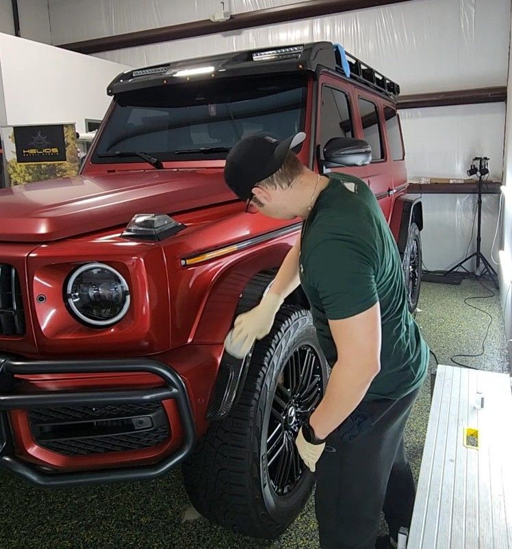 Person installing a tire on a red SUV in a garage