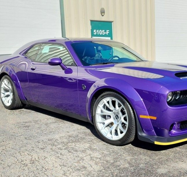 Purple Dodge Challenger parked outside a building, shown in side view.