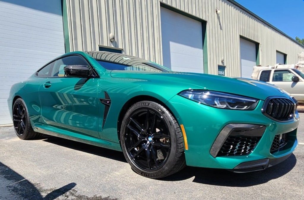 Teal sports coupe parked outside an industrial building on a sunny day