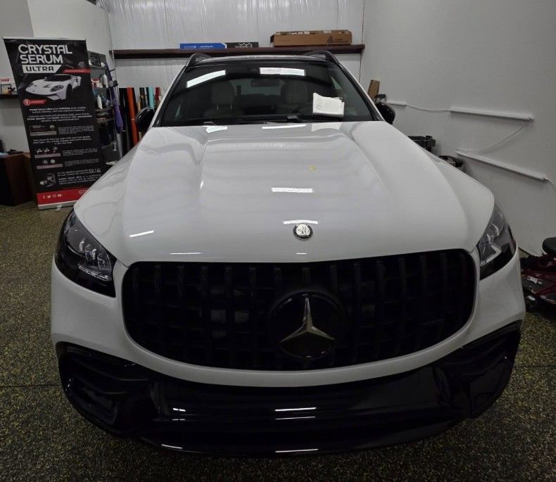 White Mercedes sedan parked indoors in a garage, front view.