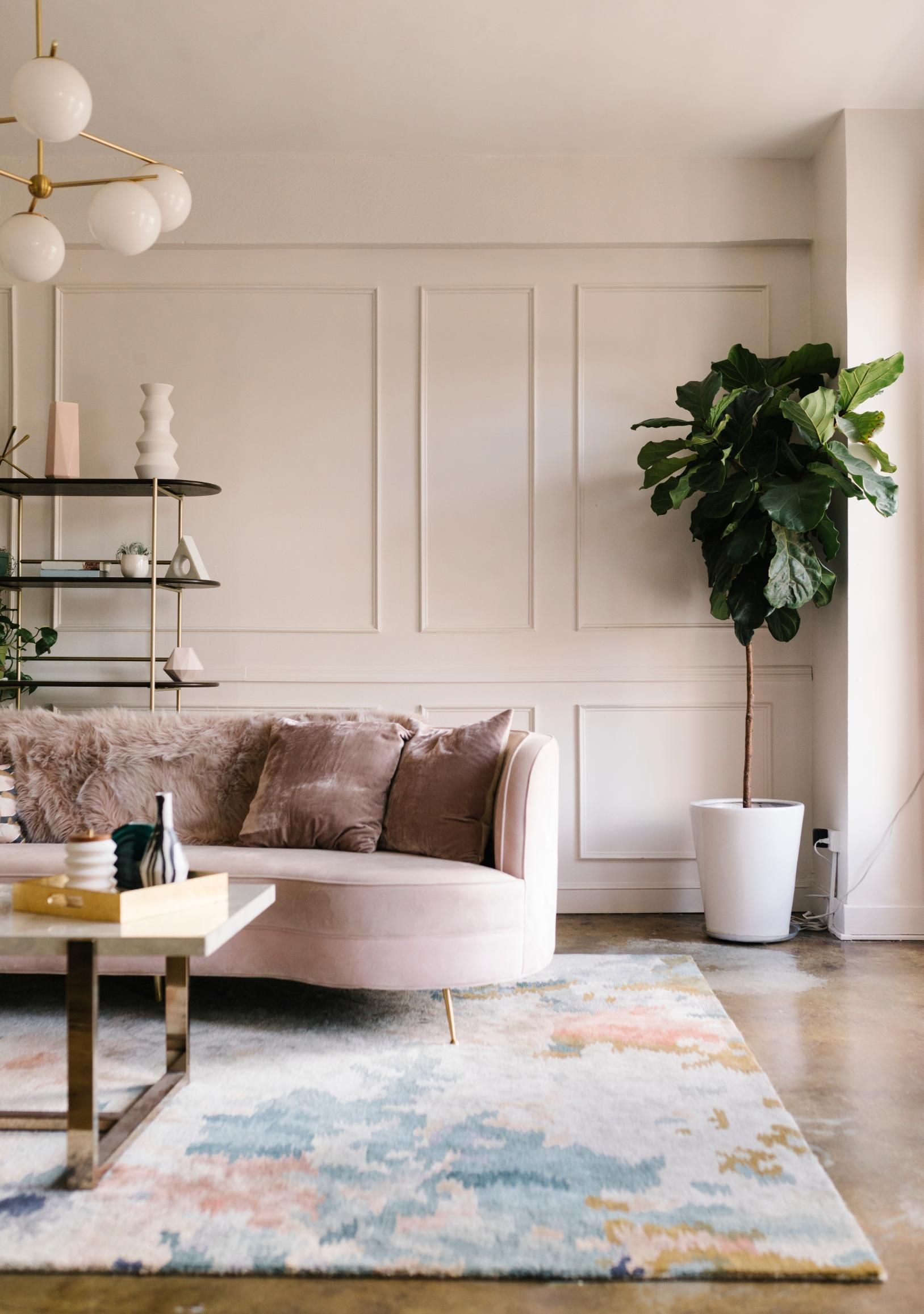 A living room with a couch, coffee table, rug, and plant.