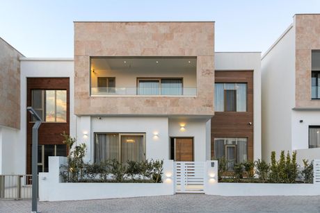 A modern house with a large balcony and a white fence.