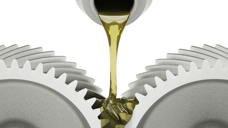 Aceite lubricante vertido entre dos ruedas dentadas engranadas.