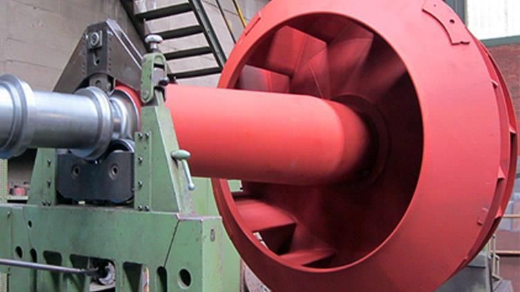 Gran ventilador rojo siendo montado en maquinaria industrial.