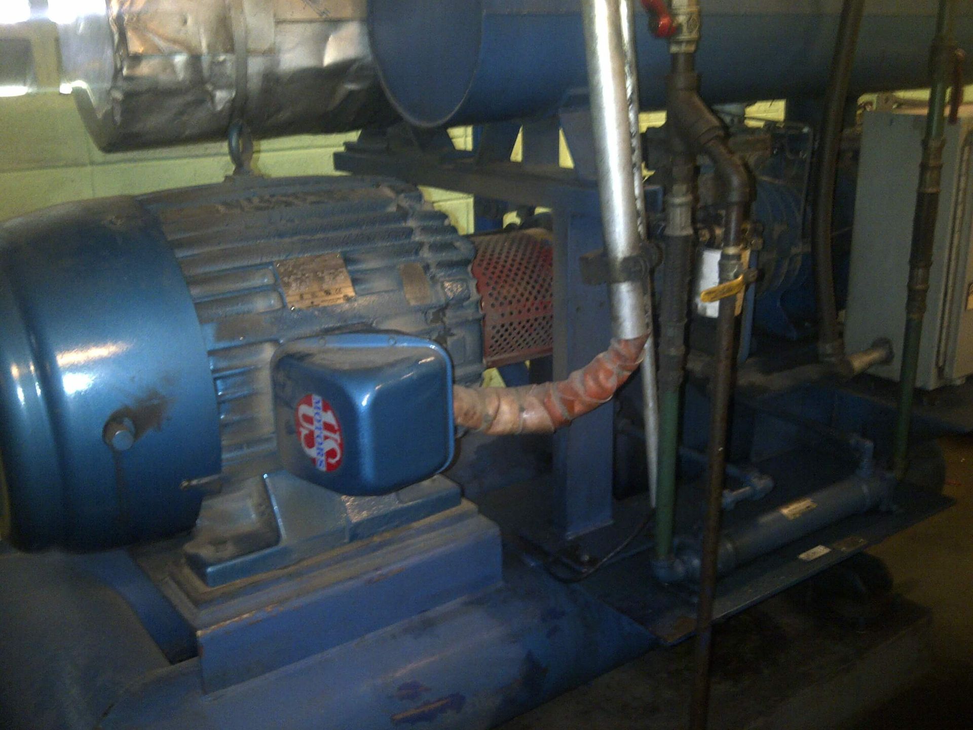 Maquinaria industrial de color azul, incluyendo un motor y tuberías, en el interior.