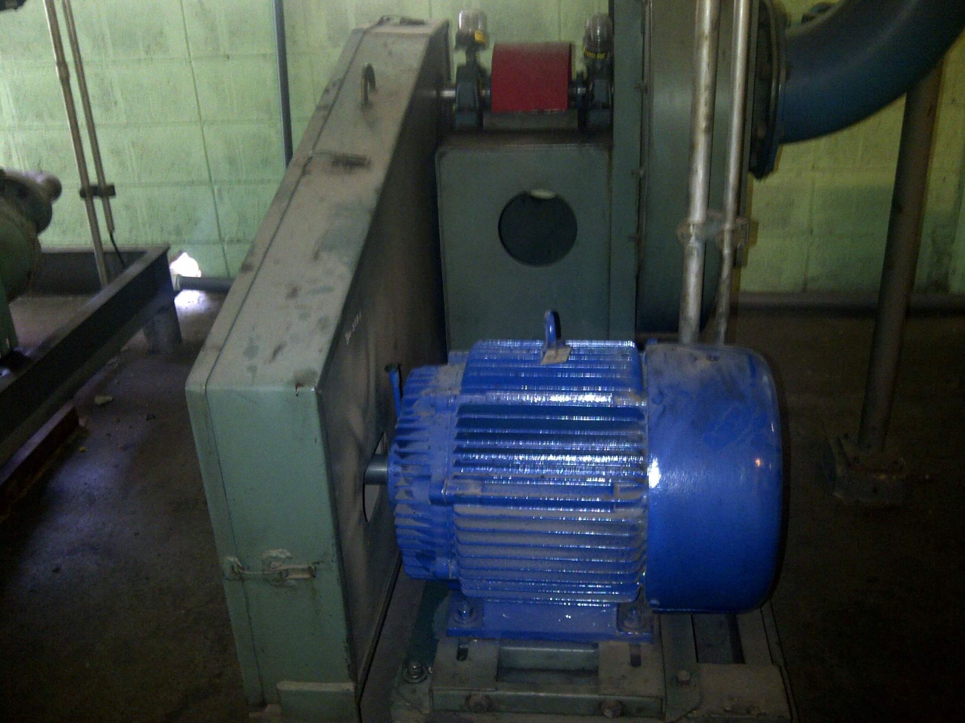 Motor eléctrico azul conectado a maquinaria industrial, en un entorno de fábrica.