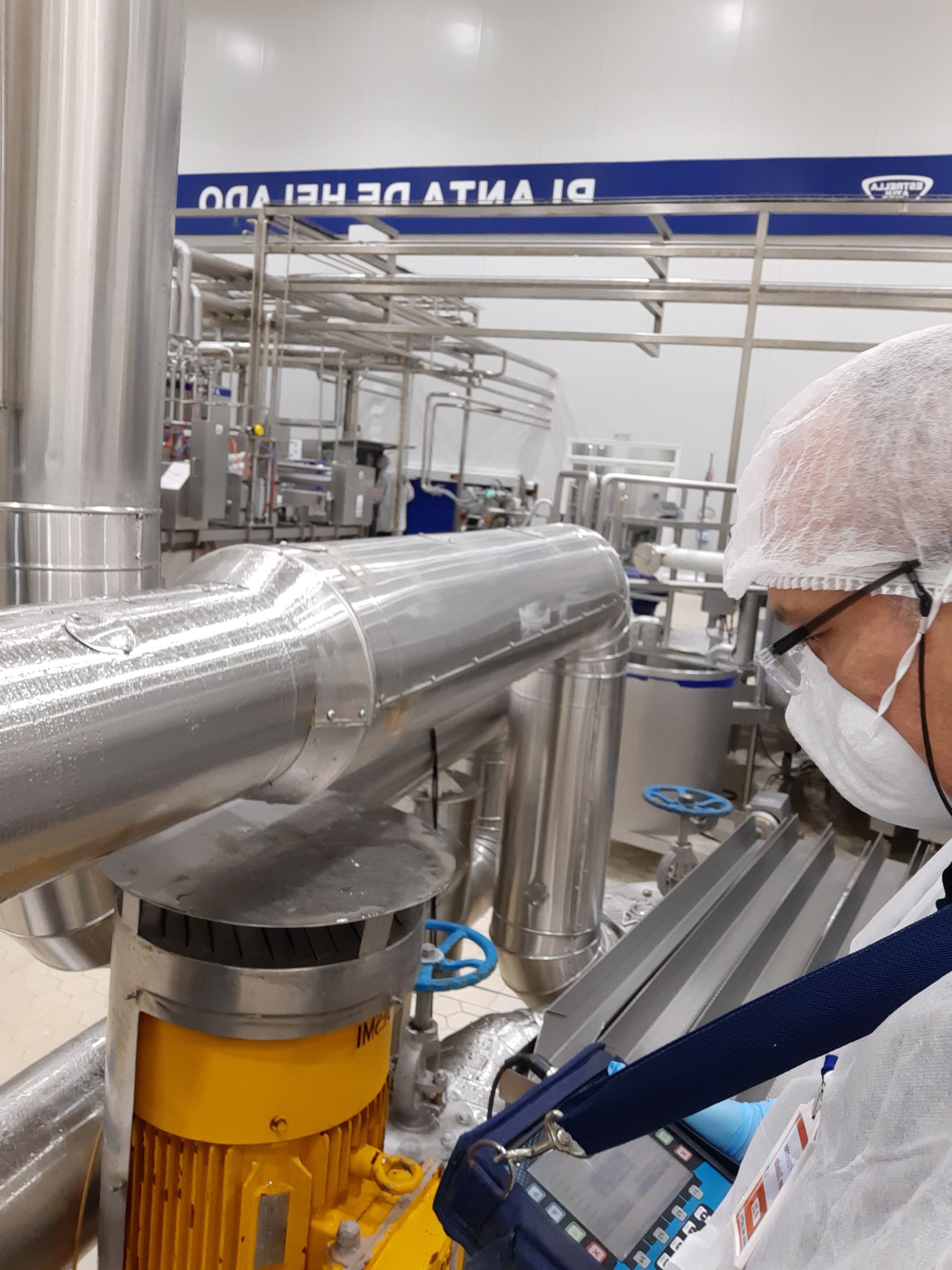 Persona con equipo de protección inspeccionando maquinaria industrial en una fábrica.