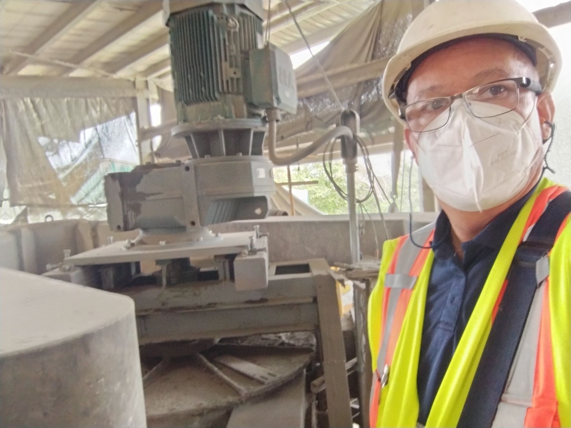 Hombre con equipo de seguridad de pie cerca de maquinaria industrial.