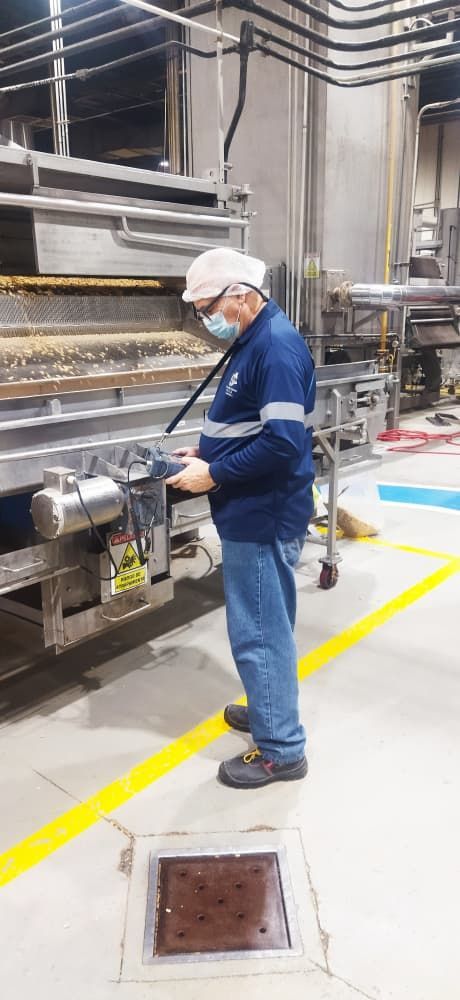 Un trabajador con uniforme azul y casco opera maquinaria en una fábrica.