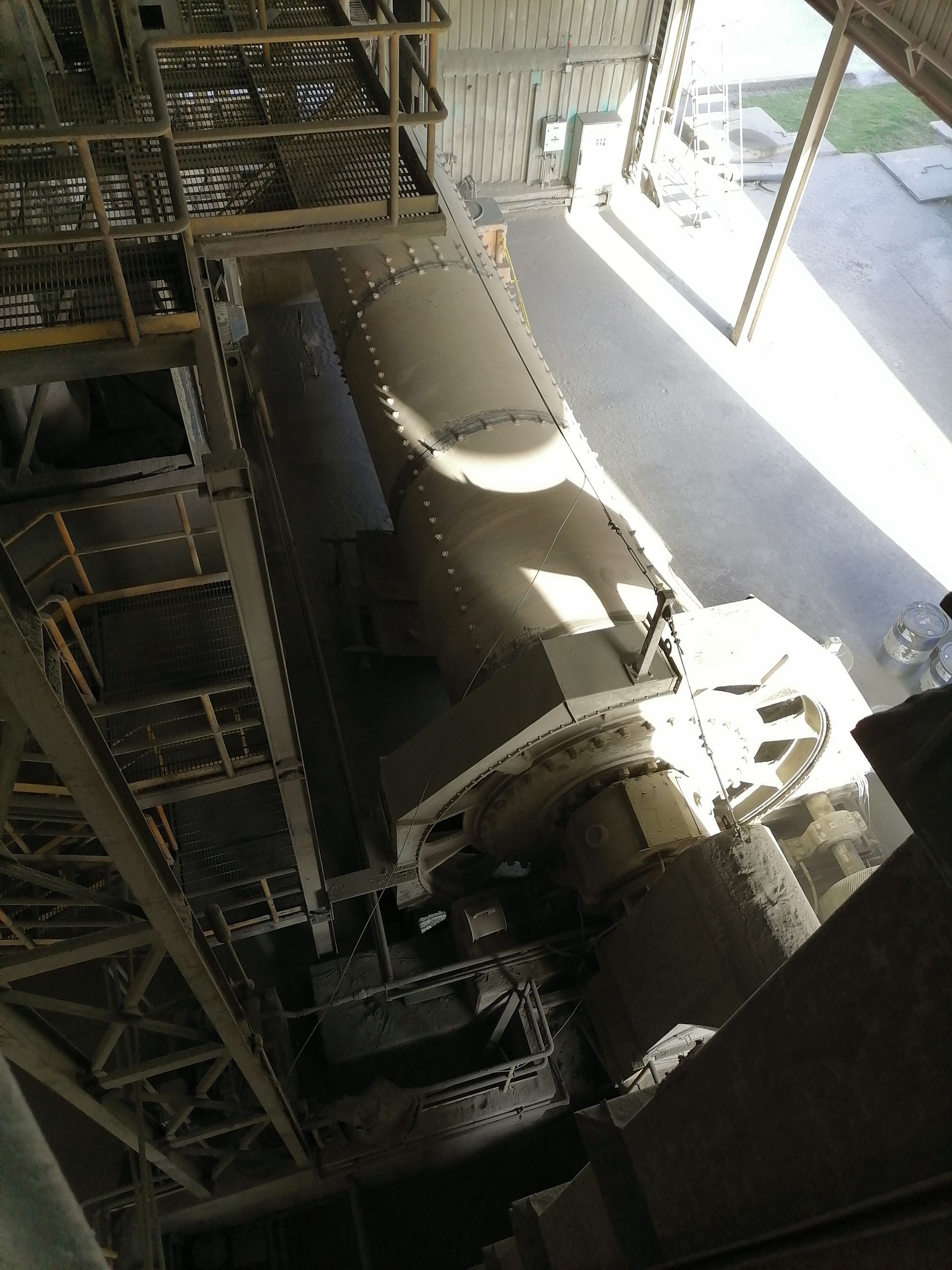 Maquinaria industrial de gran tamaño, posiblemente un horno rotatorio, dentro de un edificio de fábrica.