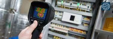 Mano sosteniendo una cámara termográfica apuntando a los componentes eléctricos de un panel