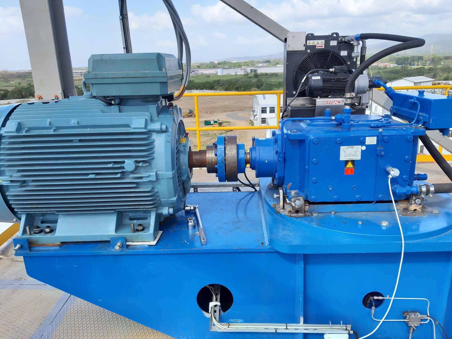 Motor y caja de cambios industriales de color azul, montados sobre una plataforma azul en el exterior.