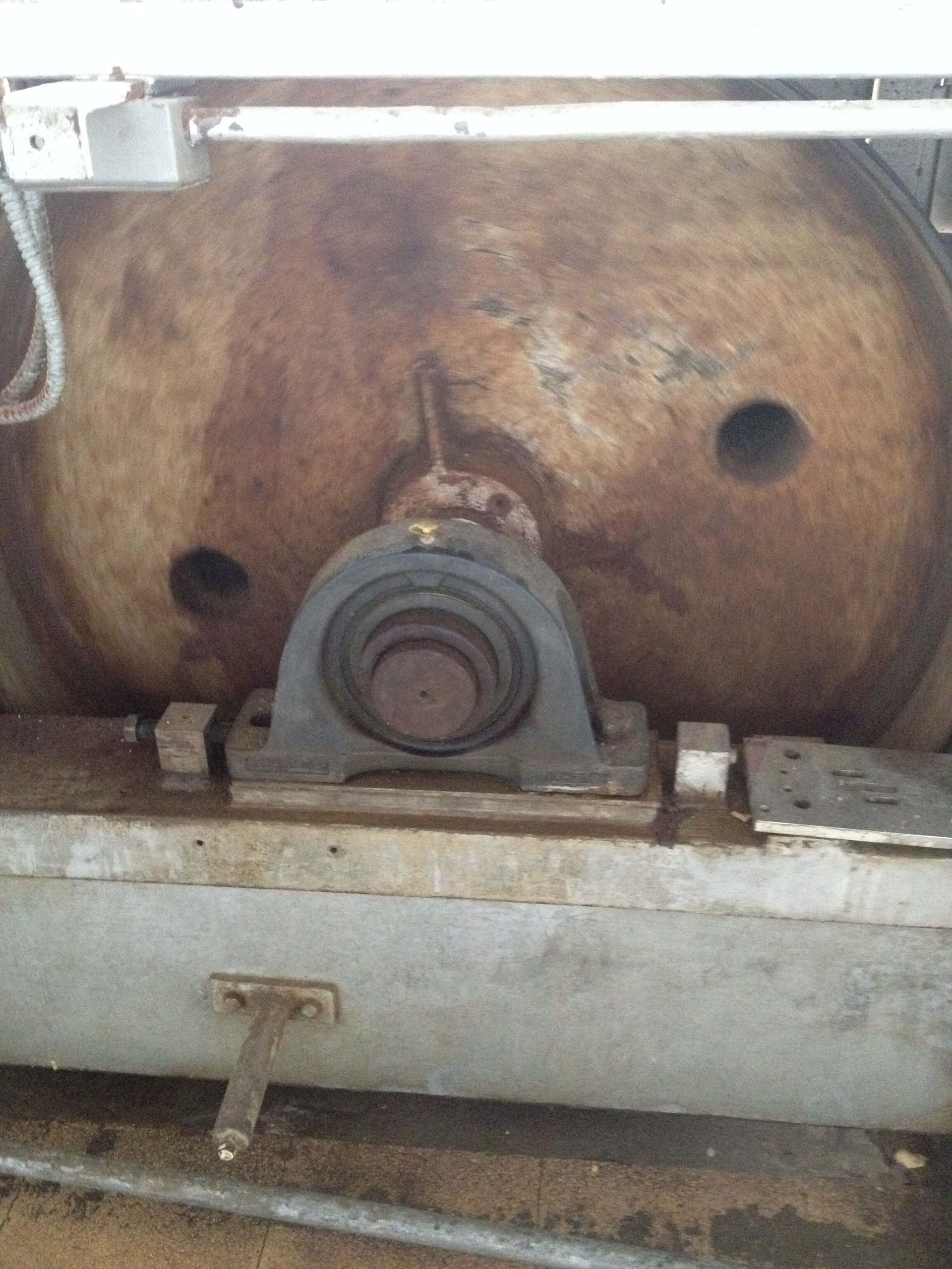 Maquinaria industrial oxidada con un cojinete en el centro y un componente circular de gran tamaño.