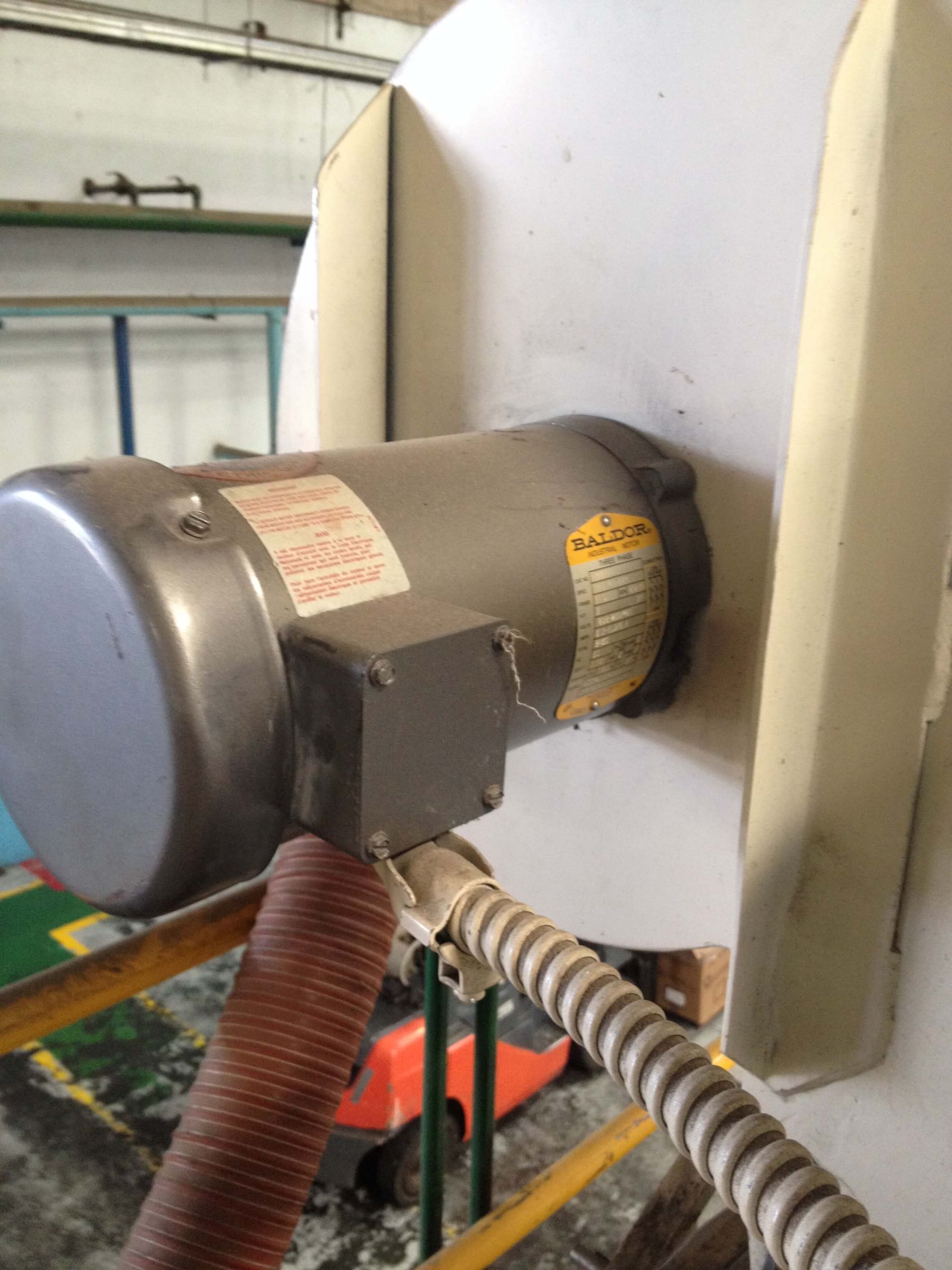 Motor eléctrico conectado a un componente blanco de la máquina. Mangueras naranjas y grises, y cableado eléctrico presente.