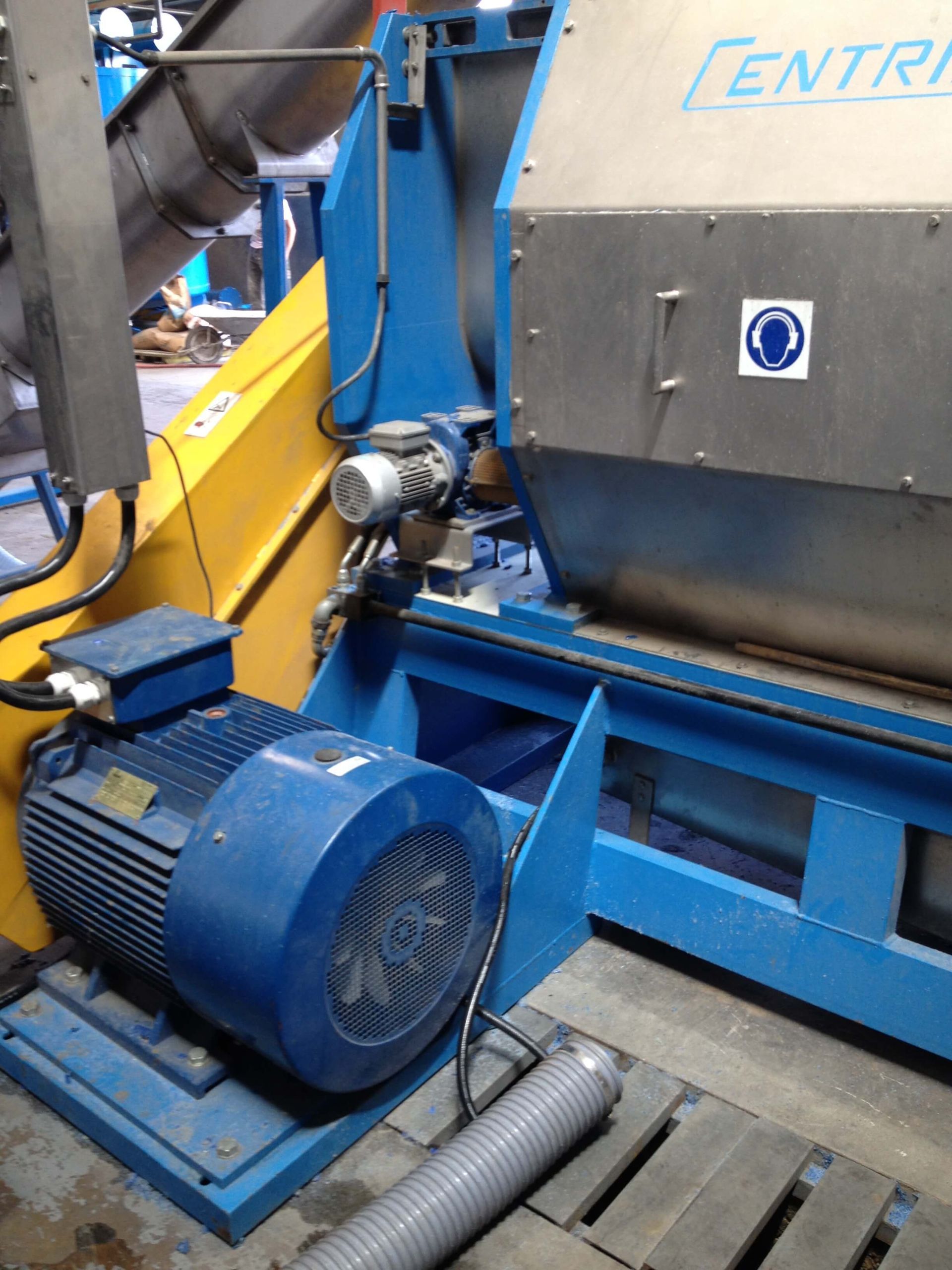 Máquina industrial de color azul y amarillo con un gran motor eléctrico.