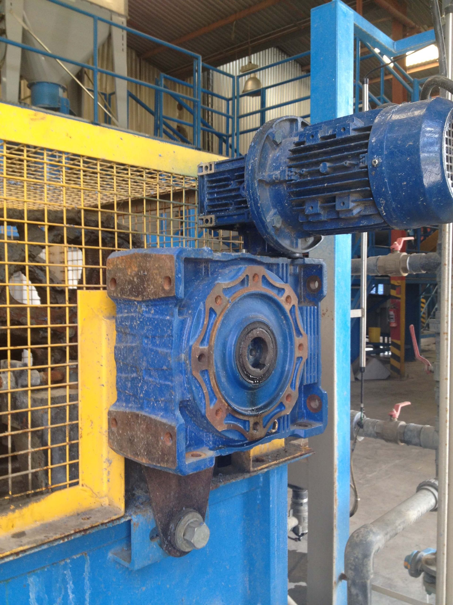 Motor industrial azul y caja de cambios unidos a maquinaria.