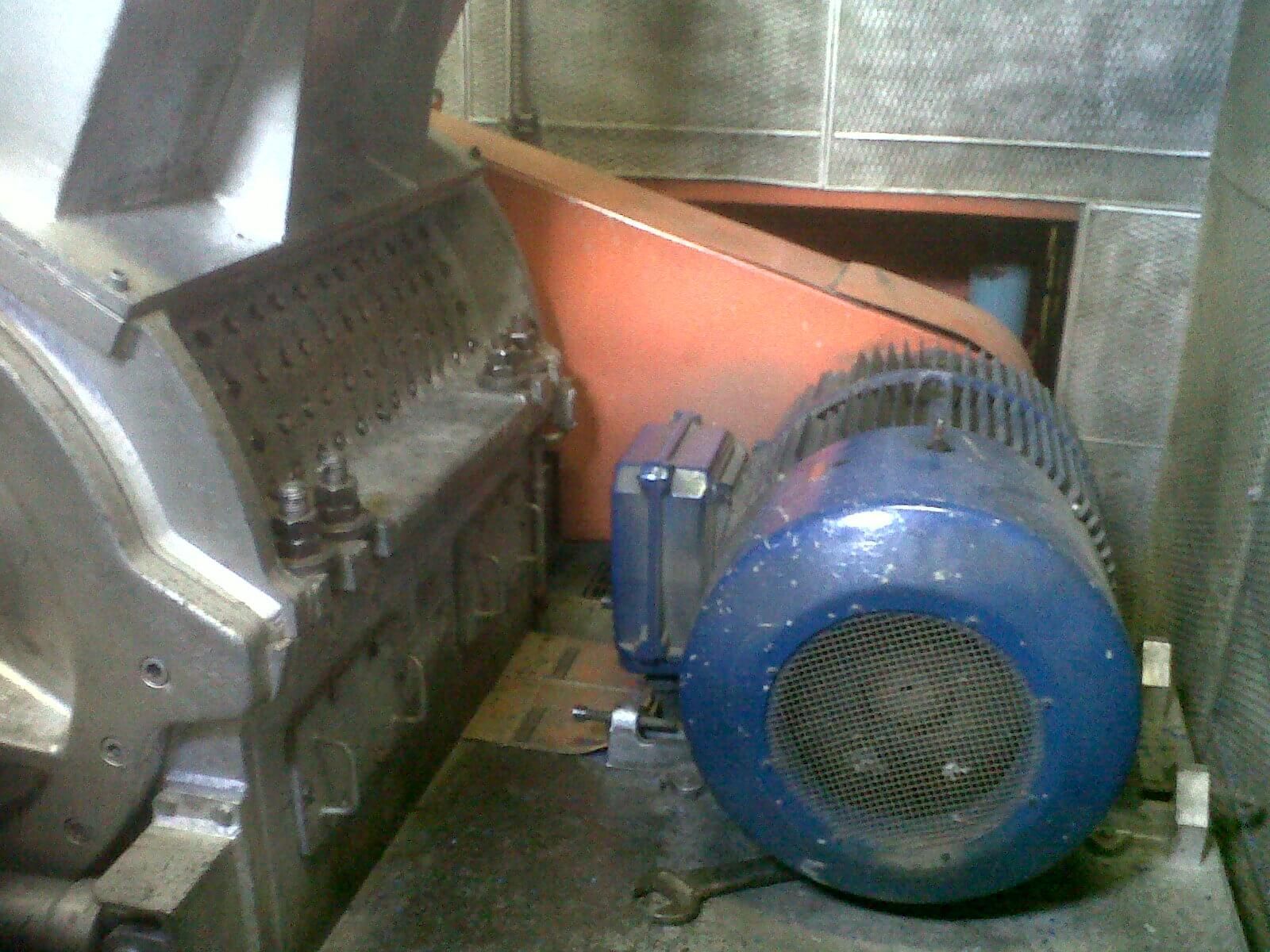 Maquina industrial con motor azul y escudo de seguridad naranja.