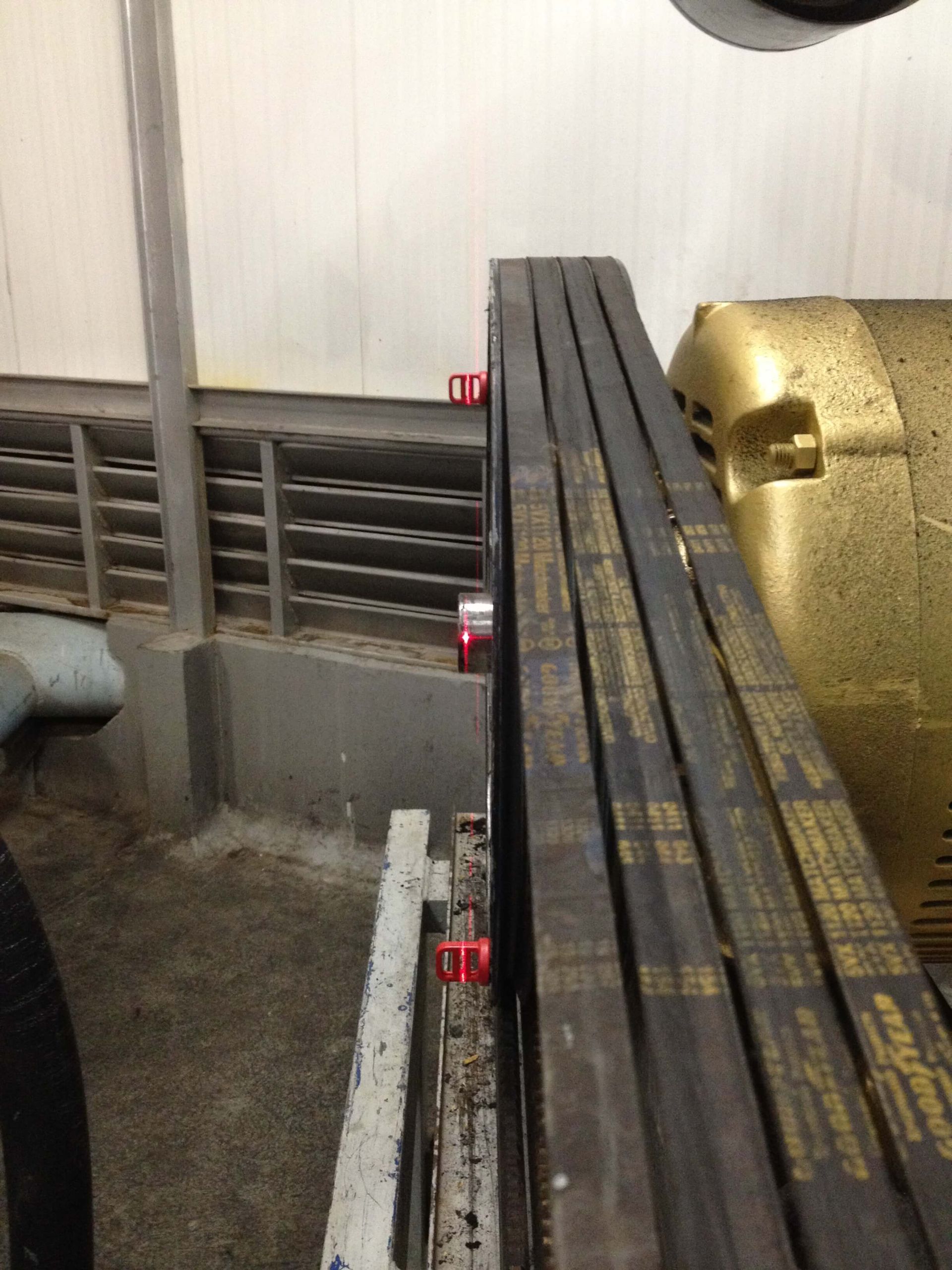 Primer plano de maquinaria industrial con múltiples cinturones negros y un motor dorado.