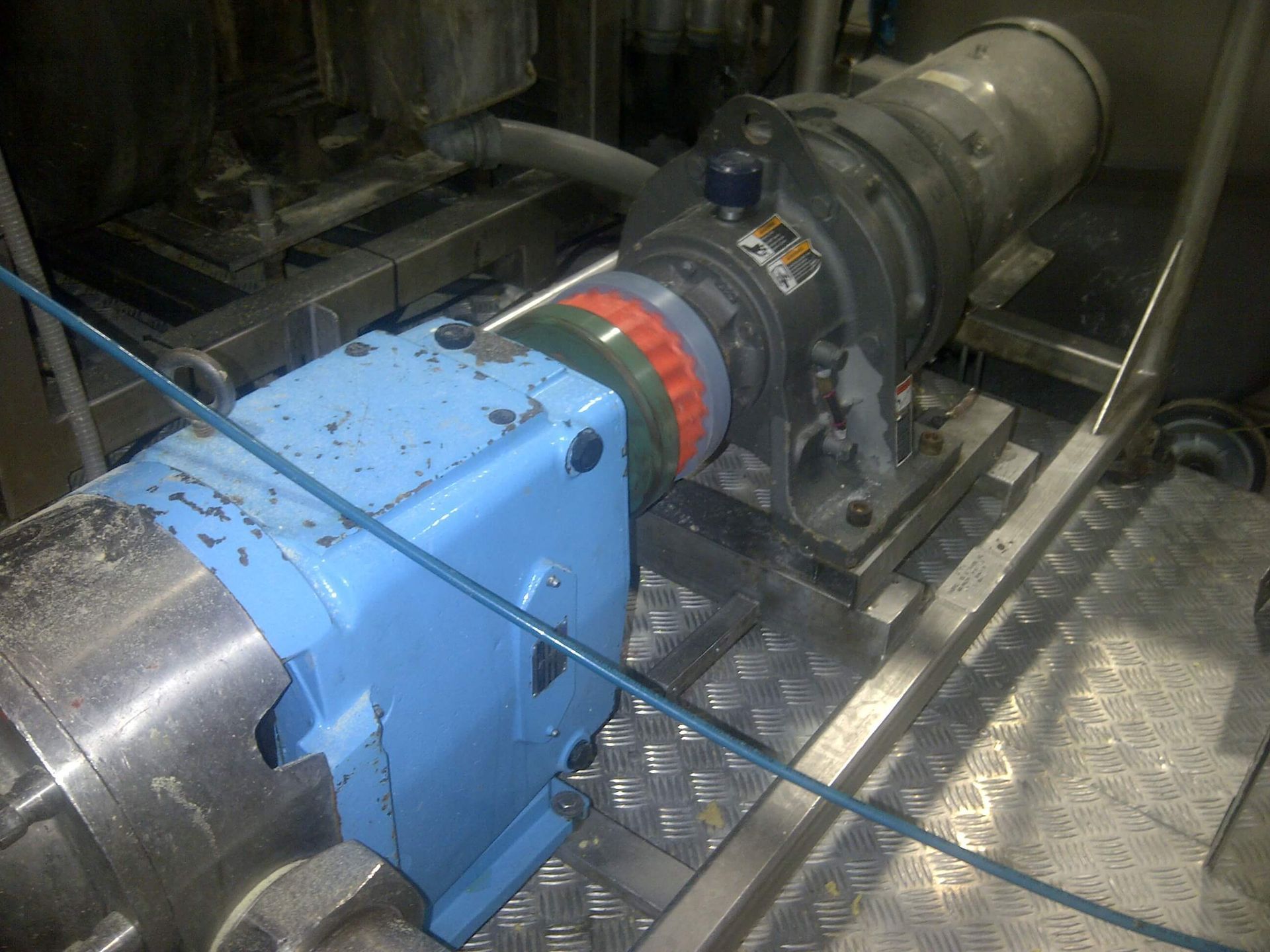 Máquina azul conectada a un objeto cilíndrico con anillos de colores, colocado sobre una superficie metálica.