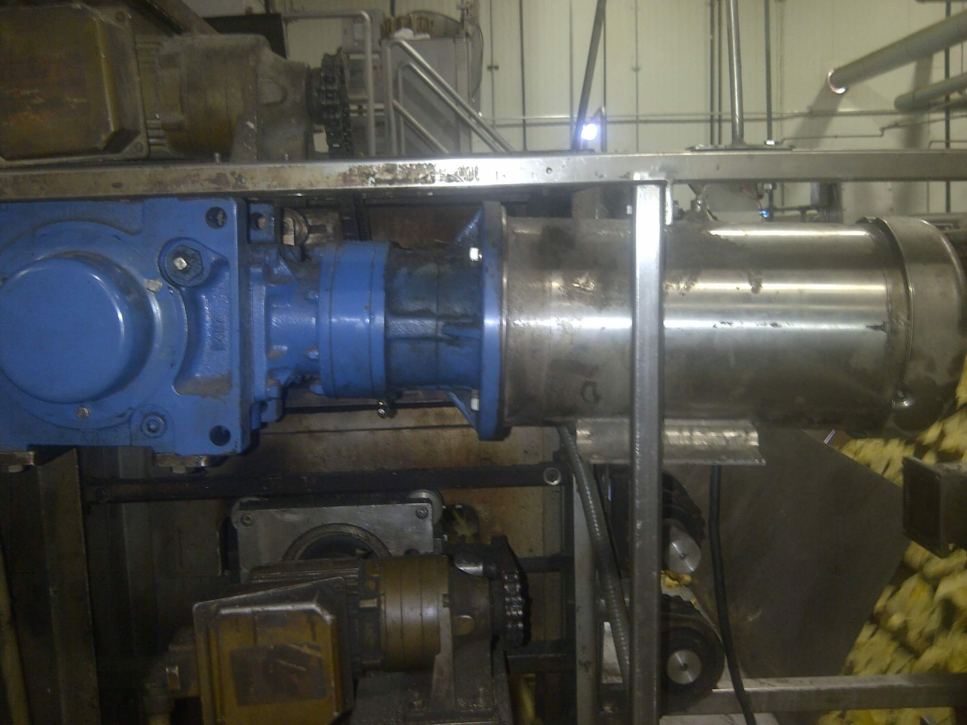 Maquinaria industrial de color azul y plata, probablemente para procesamiento de alimentos, montada sobre un marco de acero.