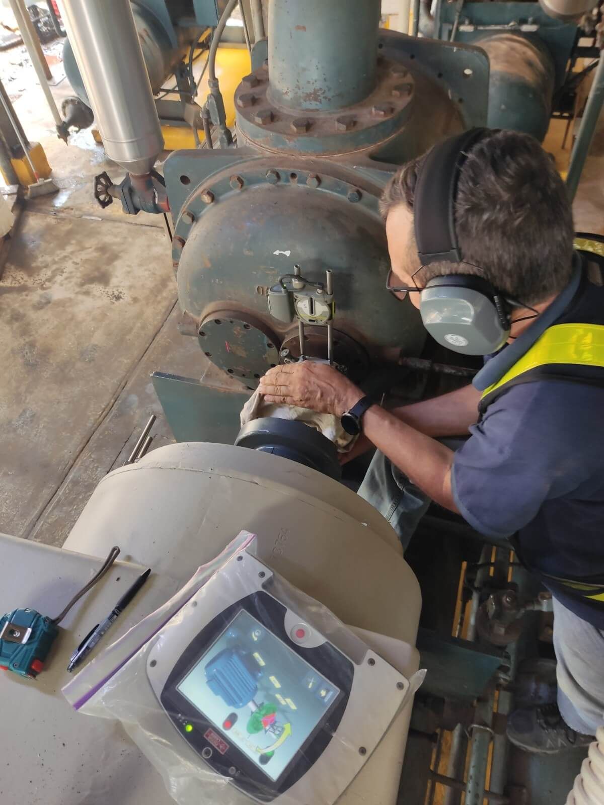 Persona con equipo de seguridad trabaja en equipo industrial, utilizando una tableta.