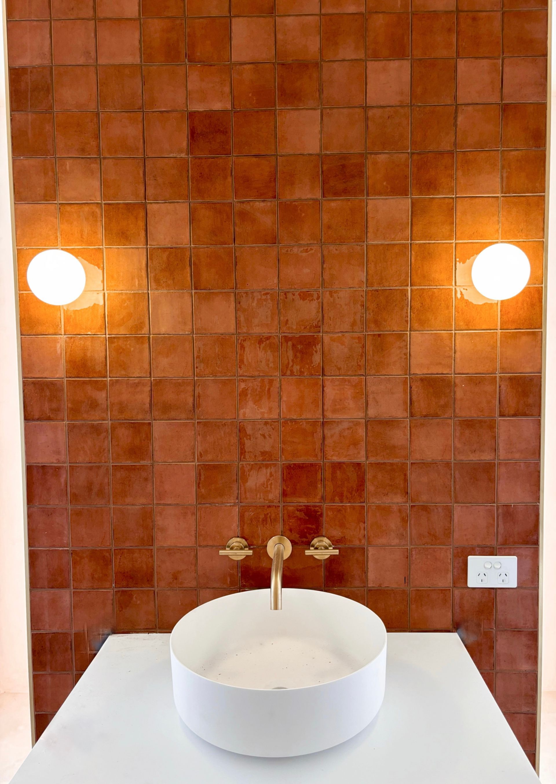  Home Electrical. A bathroom with a sink and a red tiled wall