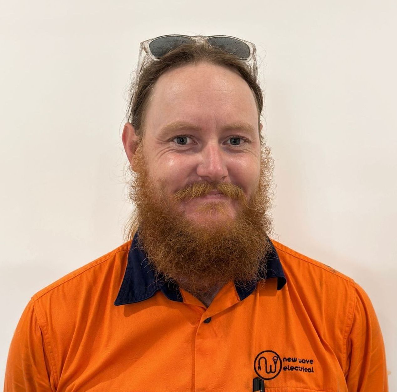 An Electrician smiling man wearing an orange shirt with the name aaron on it