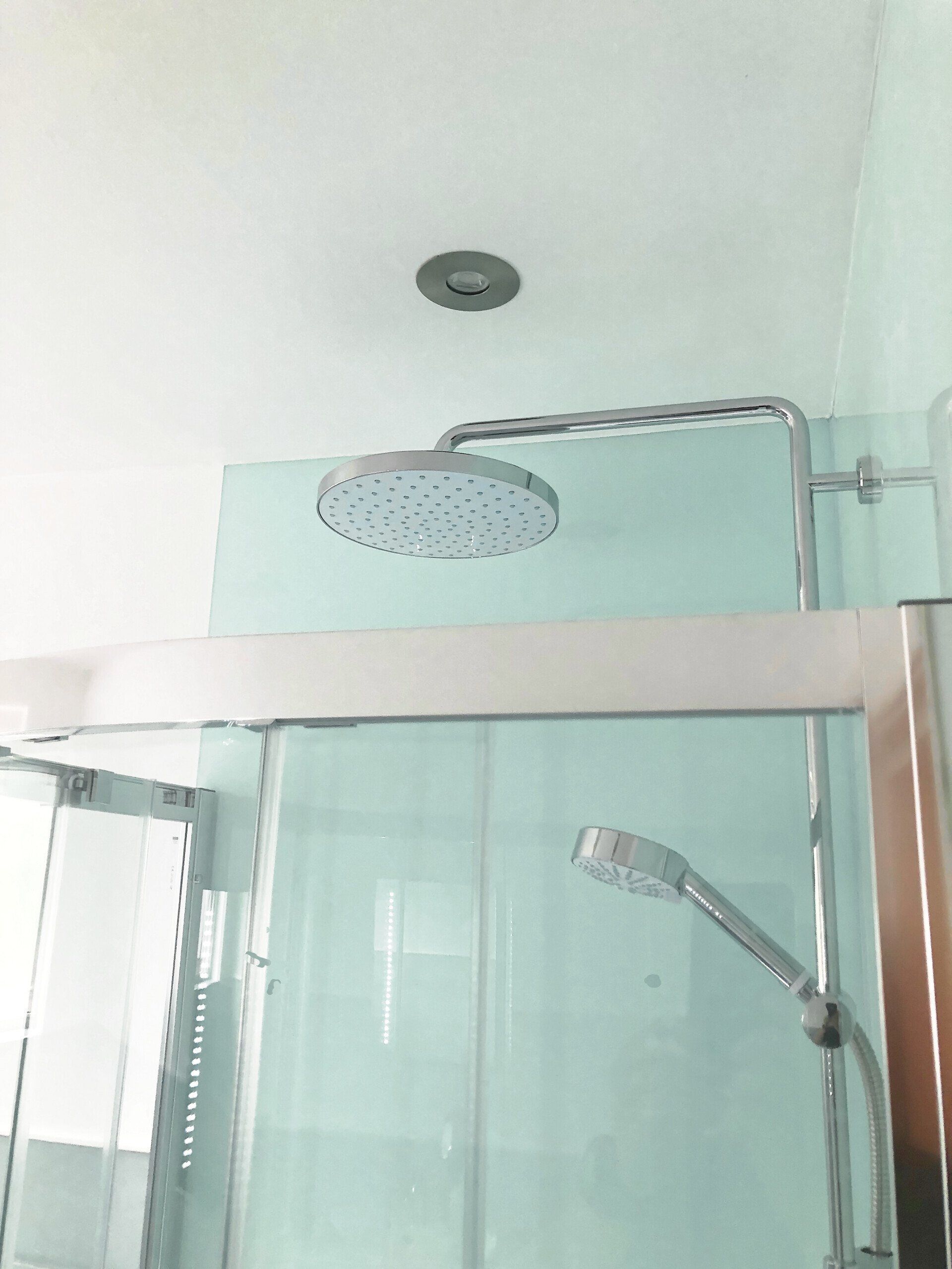A shower head is hanging from the ceiling in a bathroom.