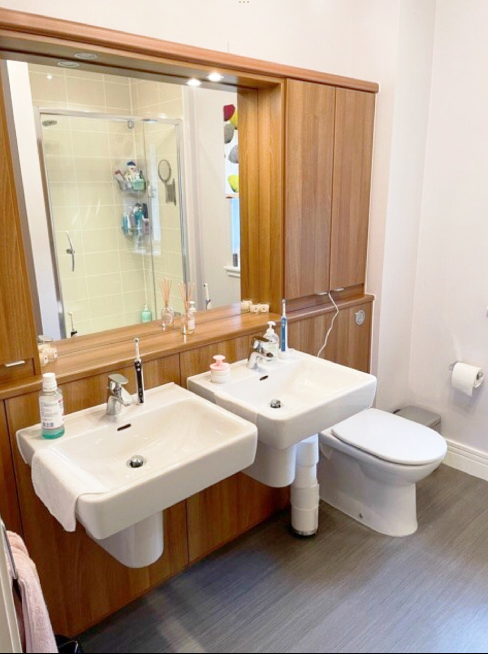 The old bathroom with two sinks, a toilet and a mirror.