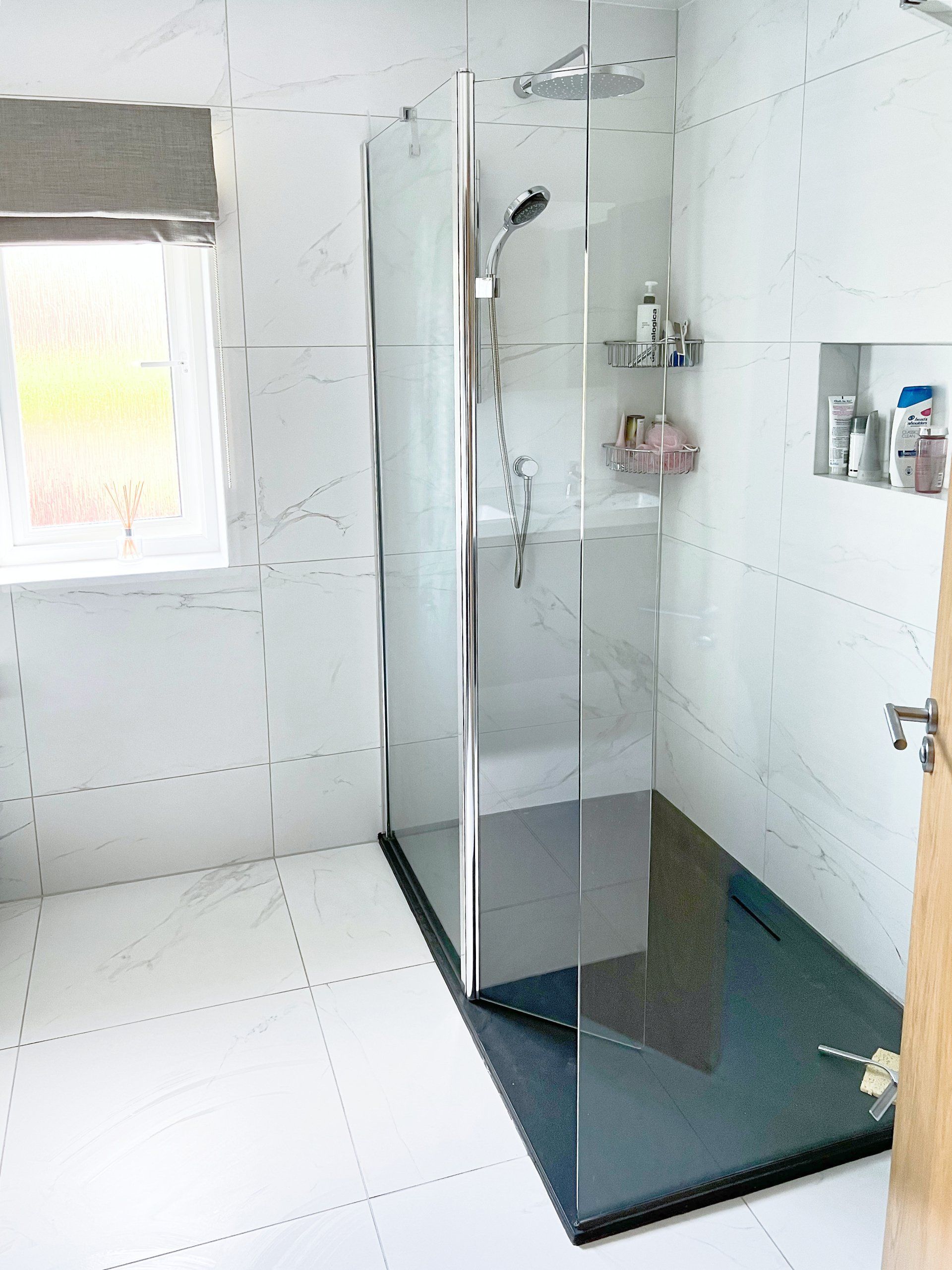 A bathroom with a walk in shower and a window.