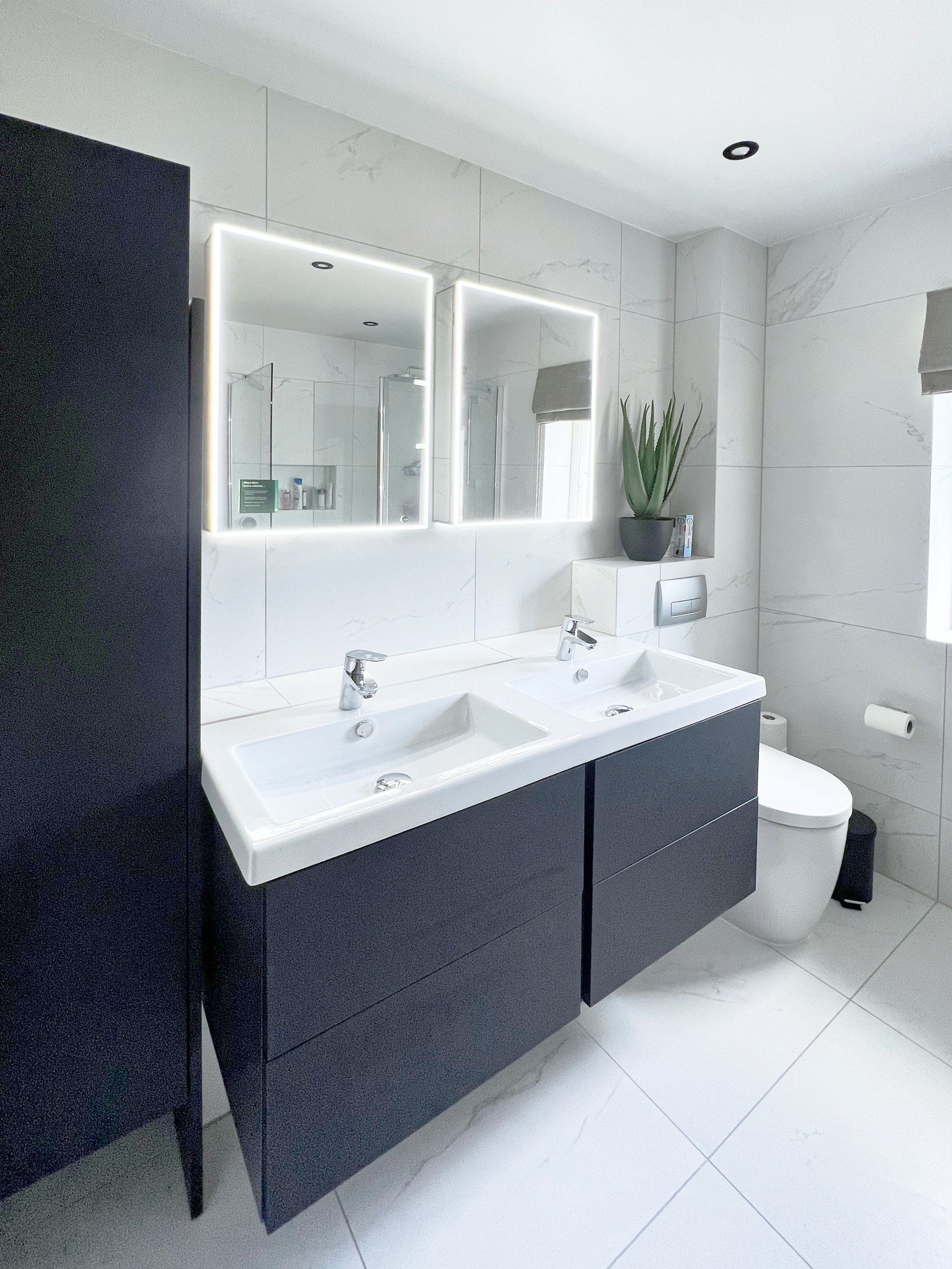 A bathroom with two modern sinks, a toilet and two mirrors.