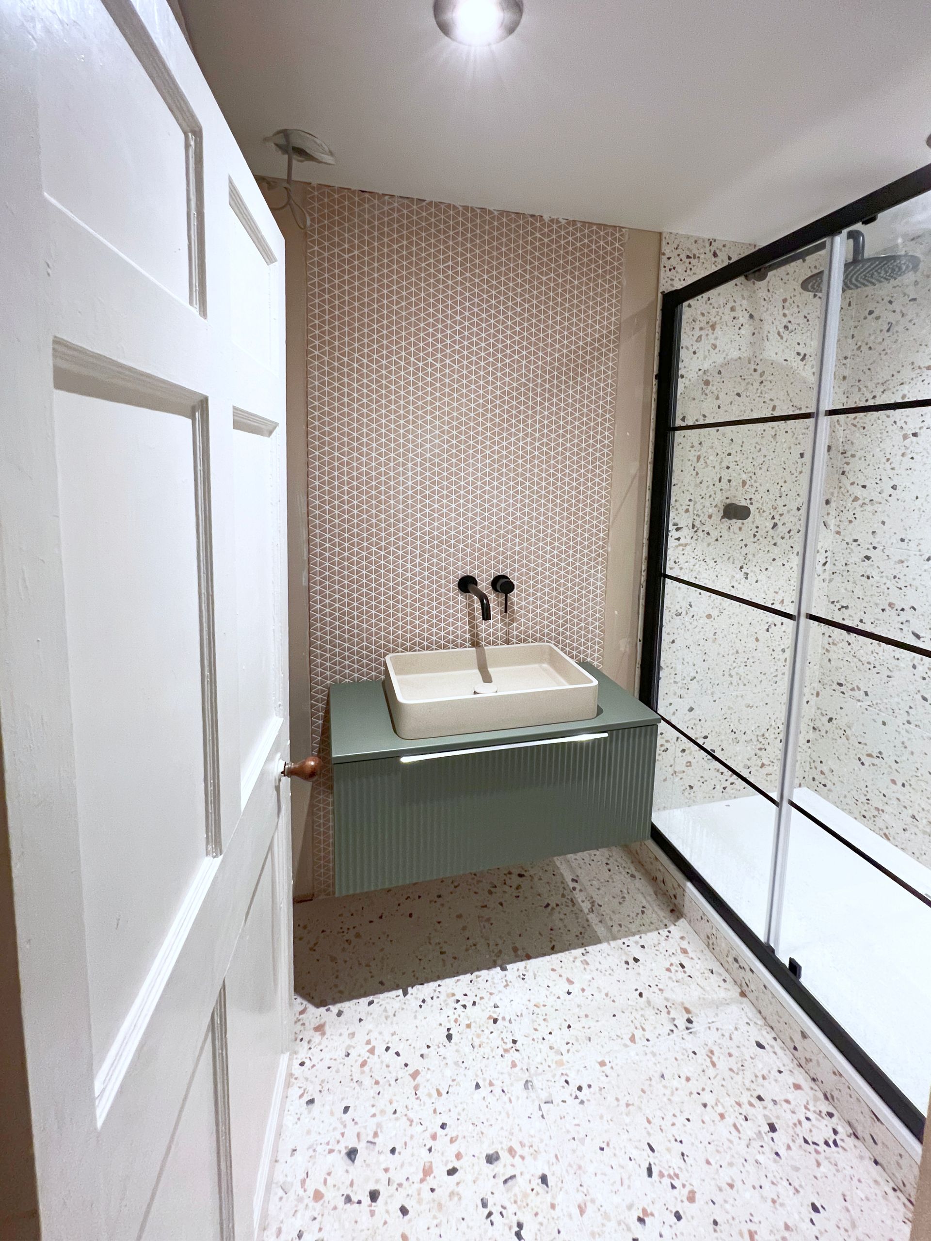 A bathroom with a sink and a shower stall.